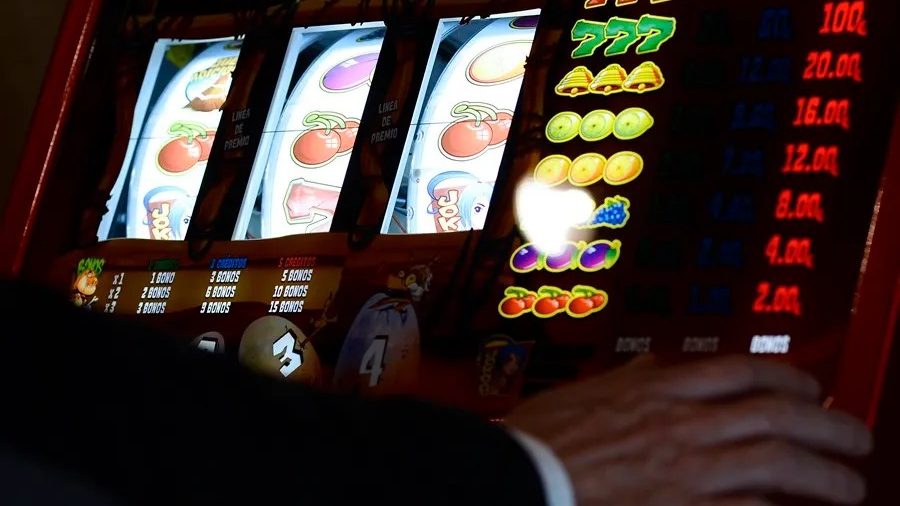 Persona solitaria frente a máquinas tragamonedas en un casino, representando la adicción al juego y sus consecuencias familiares