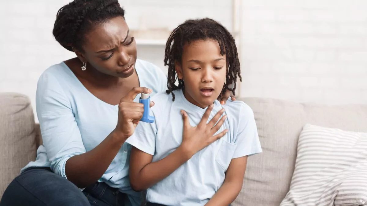 Niño usando inhalador de rescate para asma mientras su madre lo observa preocupada