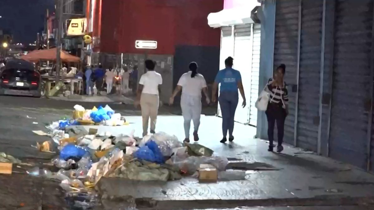 Aceras de la avenida Duarte cubiertas de basura y desechos comerciales en horas nocturnas, Santo Domingo