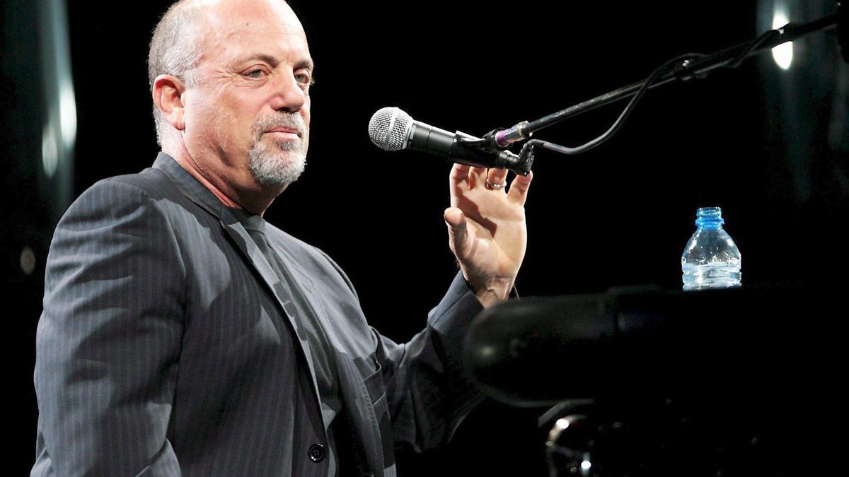Billy Joel en un concierto, con piano de fondo, afectado por hidrocefalia que le impide actuar y conducir