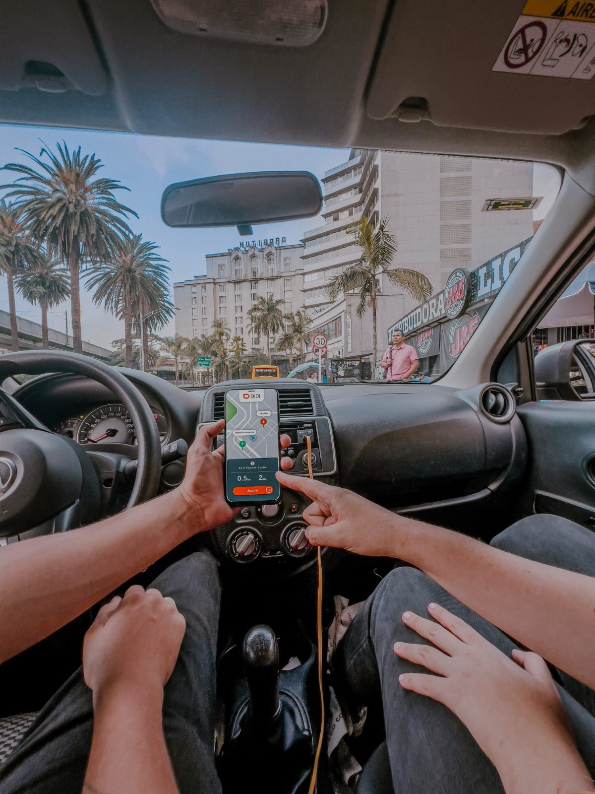 Pasajero solicitando un viaje en la app DiDi frente a una plaza comercial en Santo Domingo
