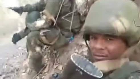 Dominicano Juan Carlos Ávila Espaillat vestido con uniforme militar posando con un fusil AK en una zona boscosa de Rusia