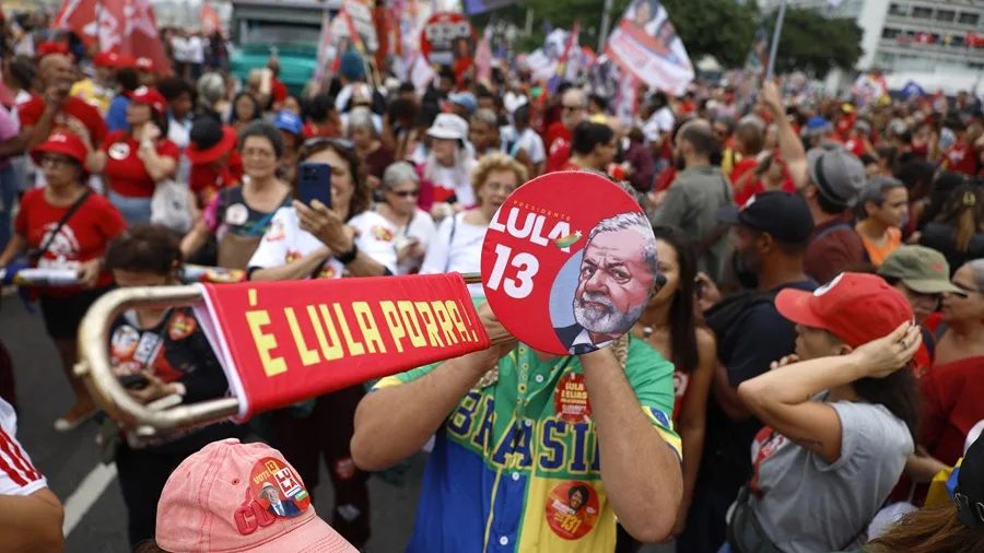 Simpatizantes de Lula da Silva marchando en la playa de Copacabana, Río de Janeiro, vestidos de rojo con carteles de apoyo