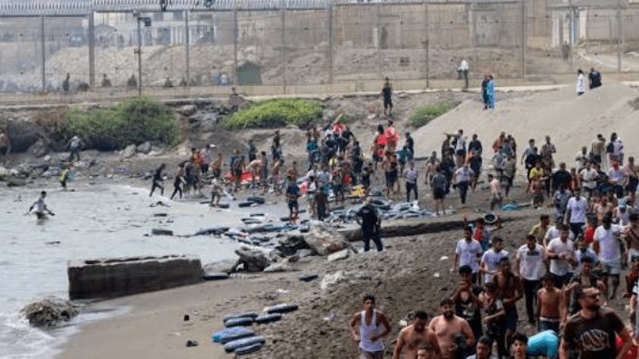 Migrantes llegando a nado a una playa del enclave español de Ceuta desde Marruecos