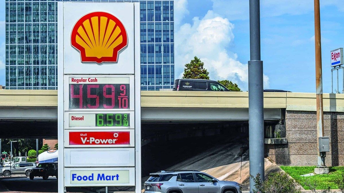 Conductor llenando el tanque en una gasolinera de Estados Unidos con precio por galón sobre los cuatro dólares en el marcador