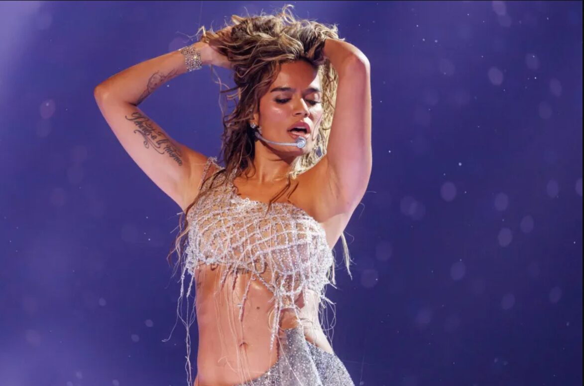 Karol G en el escenario de su gira Tropitour con luces y colores naranja