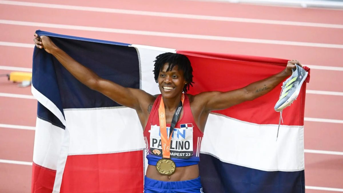 Marileidy Paulino corriendo los 400 metros en pista de atletismo con la bandera dominicana