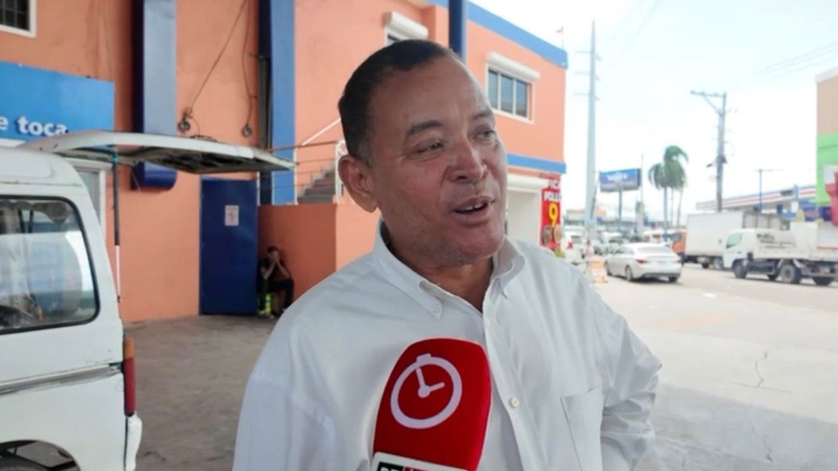 Conductor pagando en caseta de peaje en República Dominicana con letrero de Paso Rápido al fondo