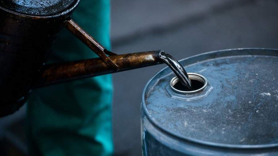 Plataforma petrolera en operación con el precio del crudo WTI subiendo en pantallas de mercados financieros