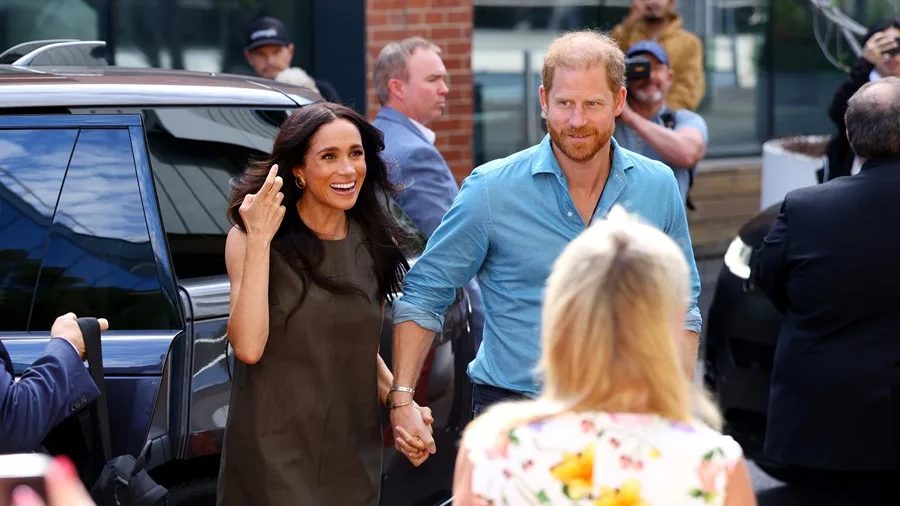 Rey Carlos III de Gran Bretaña en acto oficial, con el príncipe Enrique y Meghan Markle al fondo