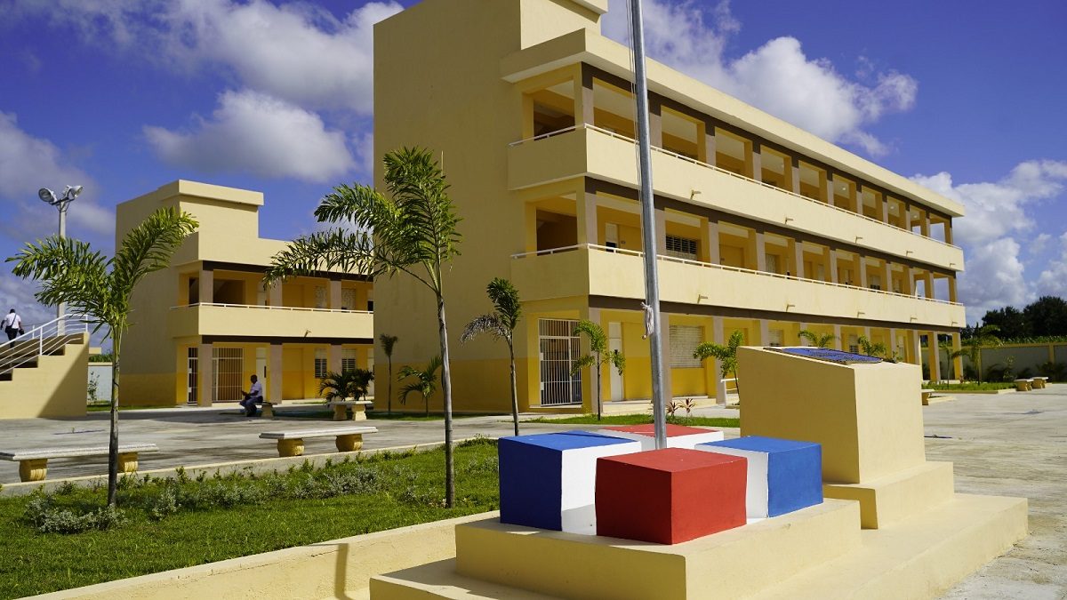 Estudiantes dominicanos entrando a su escuela el primer día del año escolar con mochilas y uniformes
