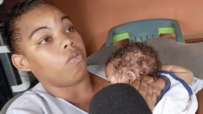 Madre sostiene foto de recién nacido frente a la Maternidad Nuestra Señora de la Altagracia en Santo Domingo