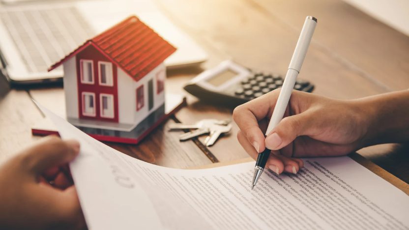 Casas residenciales en un vecindario de Estados Unidos con letrero de venta frente a altas tasas hipotecarias
