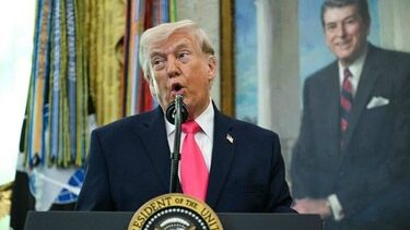 Donald Trump hablando frente a micrófonos mientras en el fondo aparece un mapa del estrecho de Ormuz