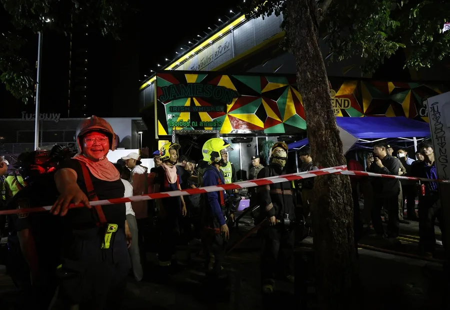 Bomberos y autoridades frente a un bar incendiado en Bangkok tras la tragedia